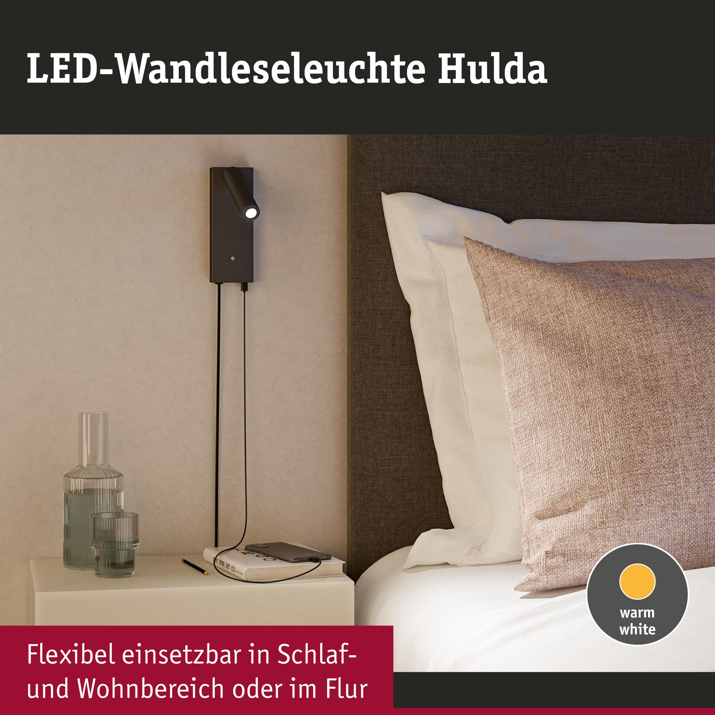 Schwarze LED-Wandleseleuchte Hulda mit warmweißem Licht neben Bett und Nachttisch im Schlafzimmer
