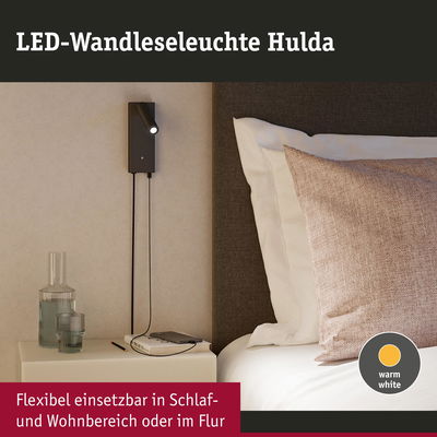Schwarze LED-Wandleseleuchte Hulda mit warmweißem Licht neben Bett und Nachttisch im Schlafzimmer