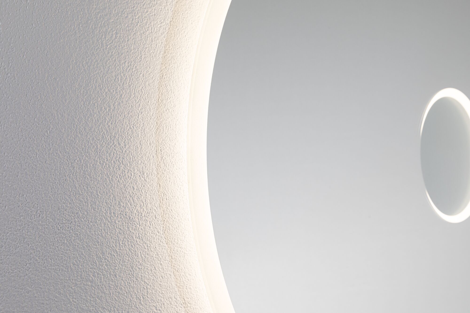 Rundes Wandspiegel mit LED-Beleuchtung und strukturierter weißer Wand im Hintergrund