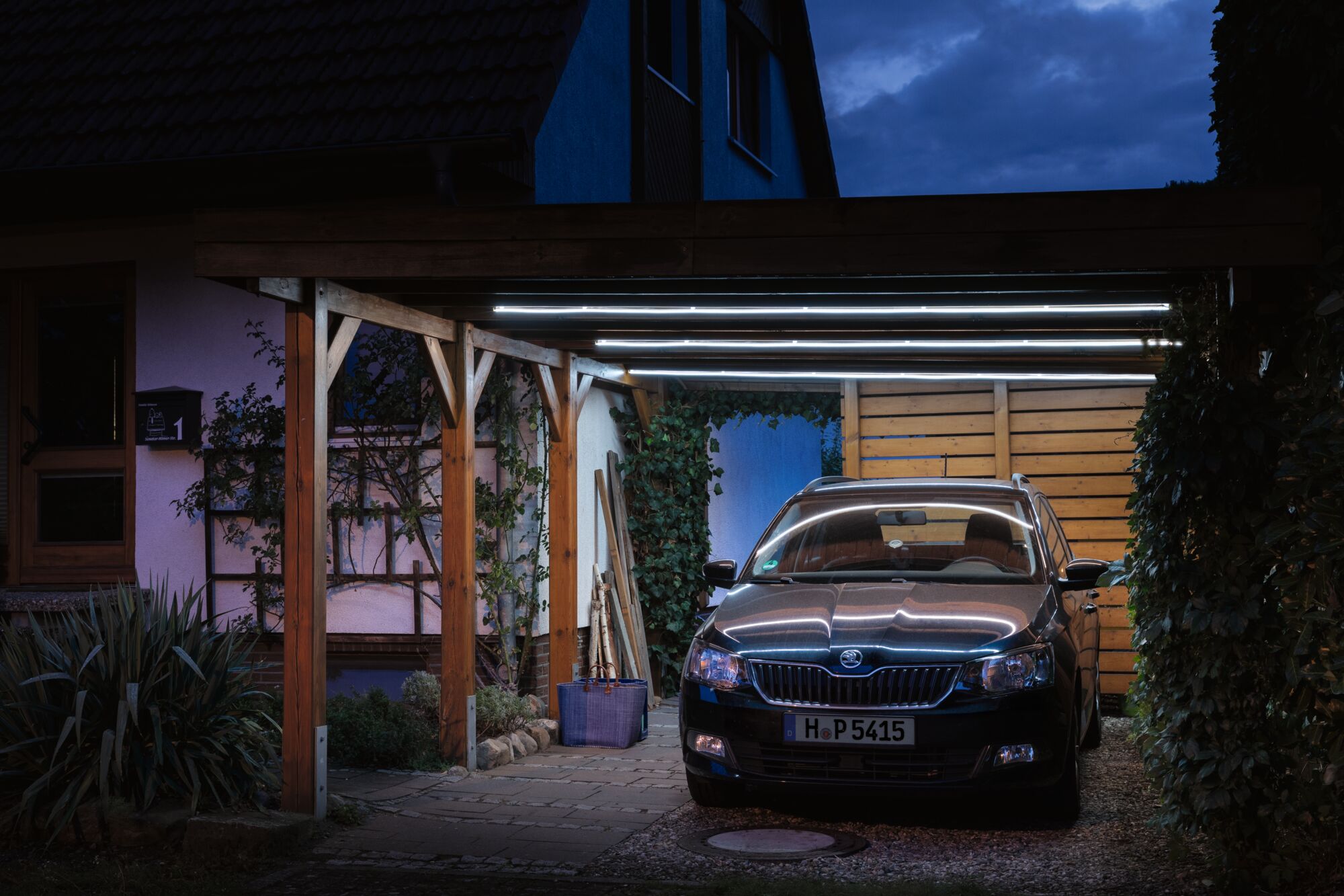 Carport mit Holzrahmen und LED-Röhrenbeleuchtung bei Nacht, modernes Außenlicht für Haus und Auto