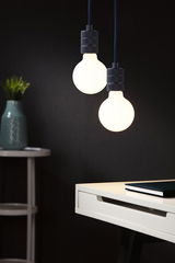 Two round LED pendant lights with matte black holders above white desk with book.