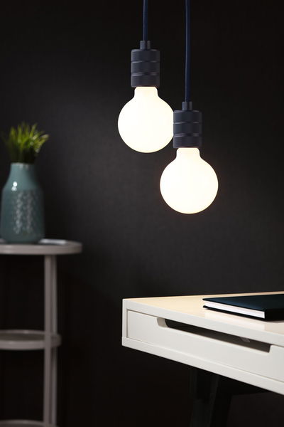 Two round LED pendant lights with matte black holders above white desk with book.