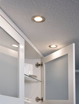 Two round recessed lights with warm white light in white kitchen setting with open cabinet.