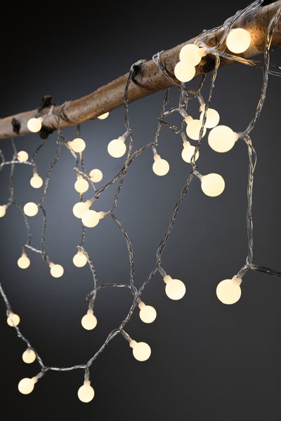 Warm white LED string lights with round bulbs on clear wire for cozy decorative lighting indoors or outdoors.