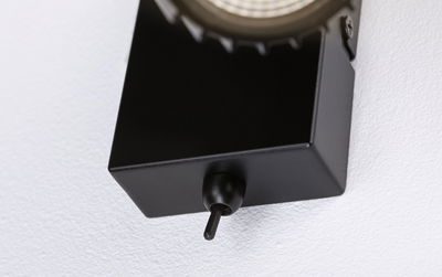 Black metal wall mount with toggle switch on textured white wall for lighting control