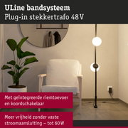 Moderne vloerlamp met zwarte metalen strepen en witte bolvormige lampen in woonkamer met fauteuil