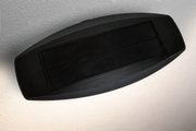 Schwarzes Solarpanel mit Kunststoffrahmen an strukturierter Wand für nachhaltige Energie.