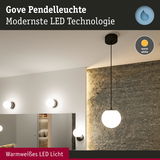 Gove Pendelleuchte mit warmweißem LED Licht und schwarzem Kabel vor grauer Steinwand