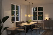 Eetkamer met houten bank, stoelen en drie warm gloeiende glazen hanglampen voor sfeervolle verlichting