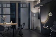 Salon moderne avec lampe sur pied noire, mobilier gris et horloge murale à cadran marbré en lumière tamisée