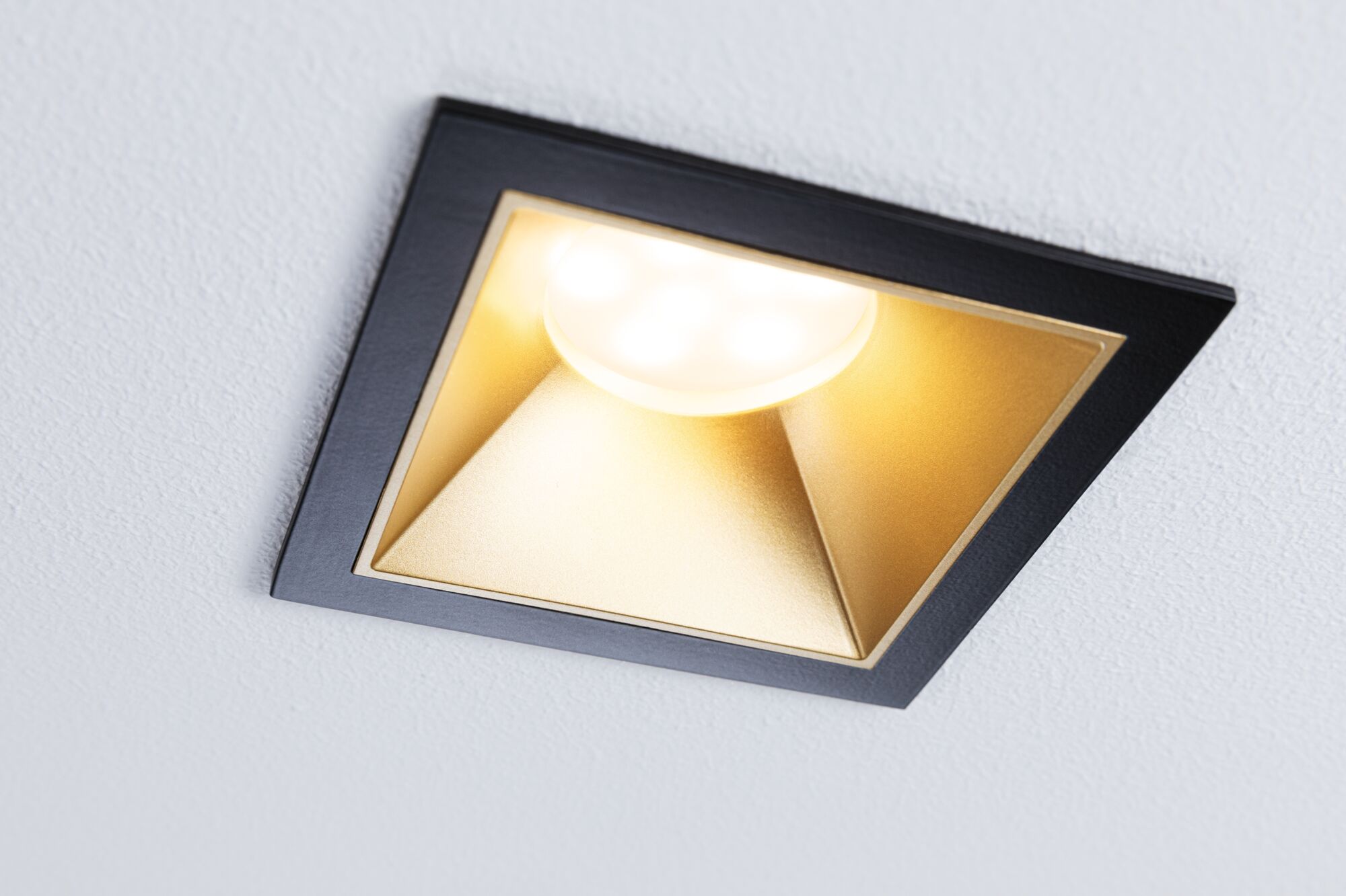 Square recessed metal spotlight in black and gold with warm white LED light for living spaces