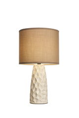 Table lamp with cream faceted ceramic base and beige fabric shade for cozy home lighting.