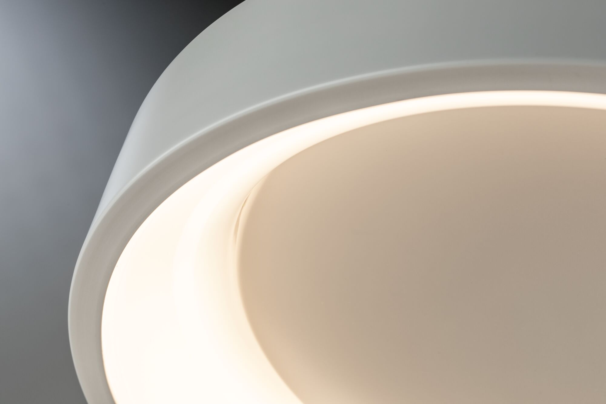 Nahaufnahme einer weißen LED-Deckenleuchte mit warmweißem Licht und modernem Design