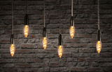 Six ampoules suspendues à filament vintage avec lumière chaude devant un mur en briques rouges, éclairage LED décoratif