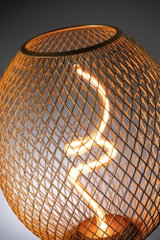 Modern table lamp with spiral LED light and warm glow inside copper-colored metal mesh shade