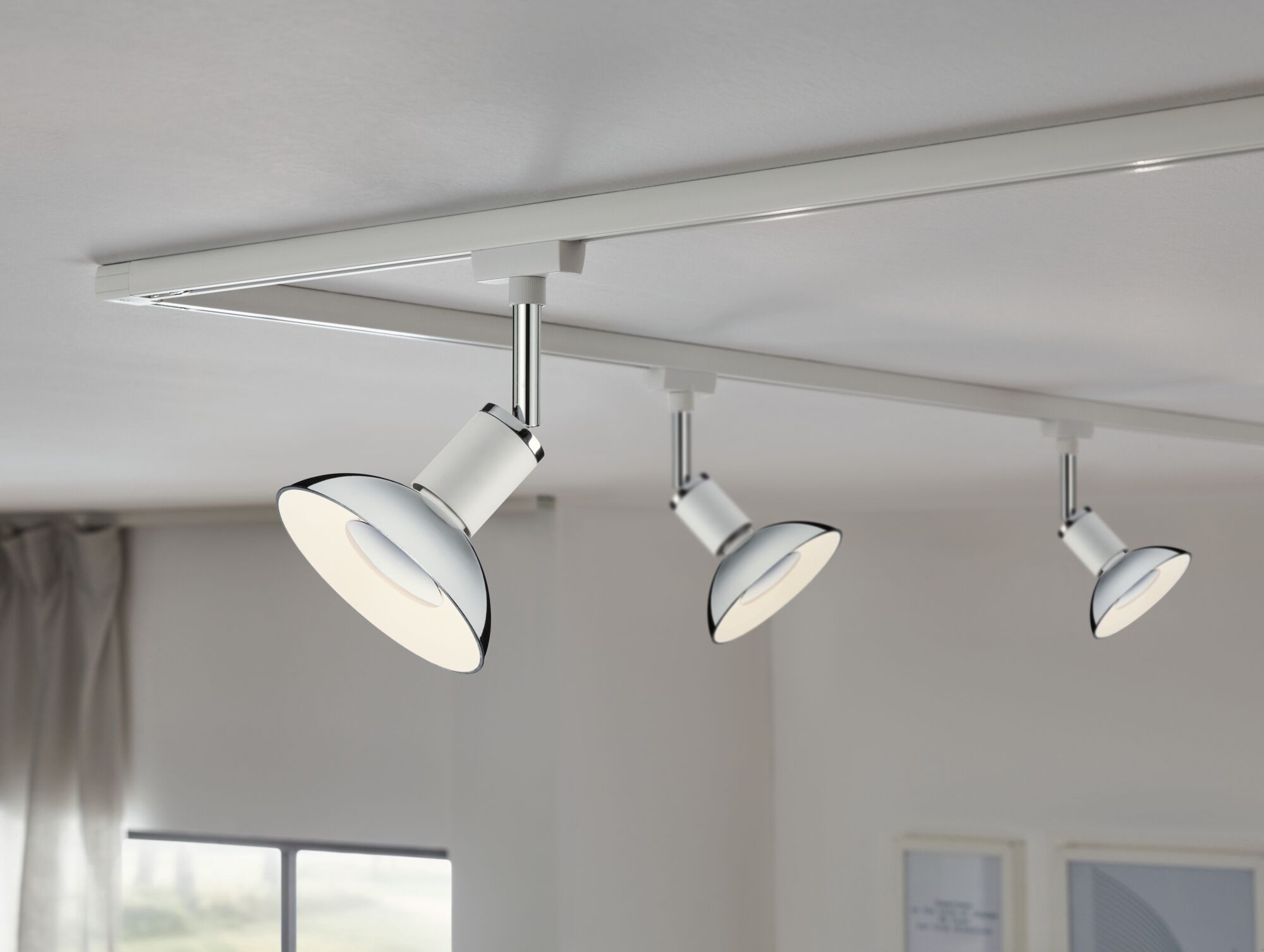 Three white LED ceiling spotlights with chrome accents on white track for modern room lighting