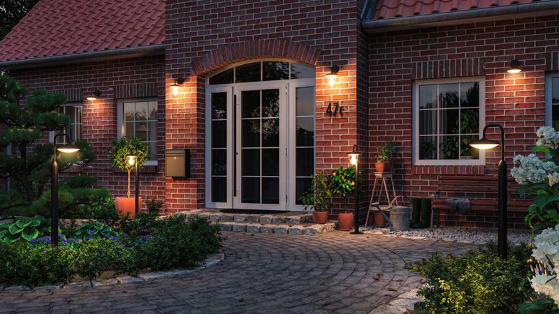 Outdoor insect-friendly lighting on red brick house and garden path at dusk for sustainable garden illumination