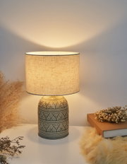 Lampe de table en céramique avec abat-jour en tissu crème et motif floral, lumière chaleureuse.