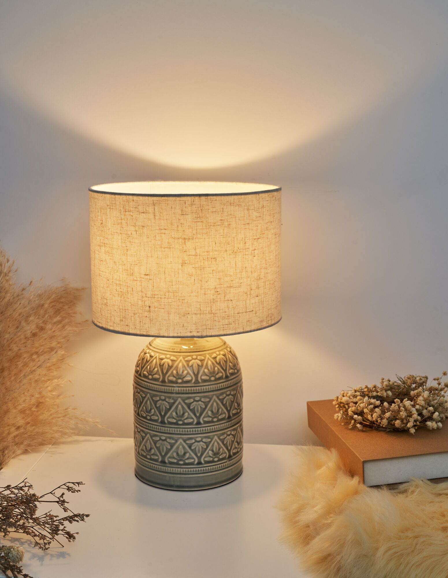 Lampe de table en céramique avec abat-jour en tissu crème et motif floral, lumière chaleureuse.