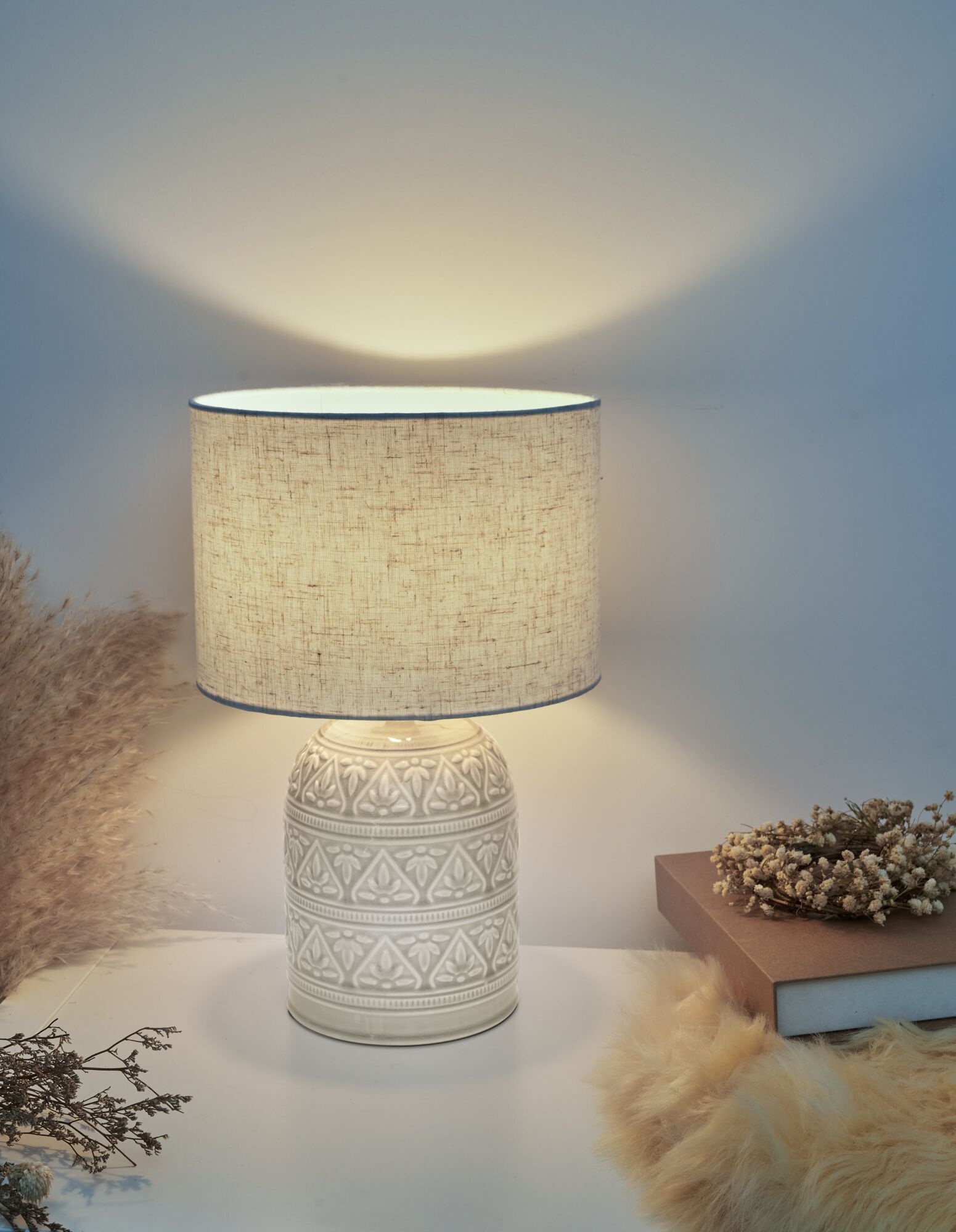 Keramik-Tischlampe mit cremefarbenem Stoffschirm und floralem Muster, warmes Wohnlicht.
