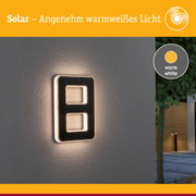 Solarleuchte mit warmweißem Licht an grauer Wand, modernes Design für Außenbeleuchtung