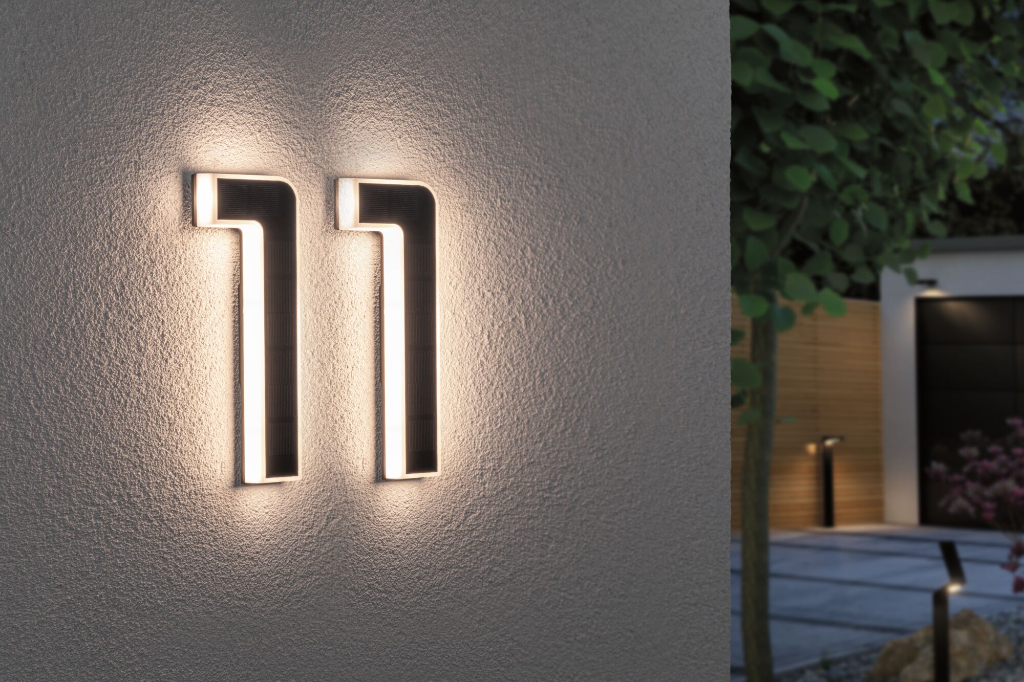 Moderne sort LED-husnummerlampe med varmt hvidt lys monteret på ydervæg ved indgang