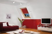 Moderne woonkamer met rode bank, rood dakraamrolgordijn en witte tv-kast op houten vloer