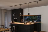 Modern kitchen with black wood island and wooden countertop, three black pendant lights on track system.