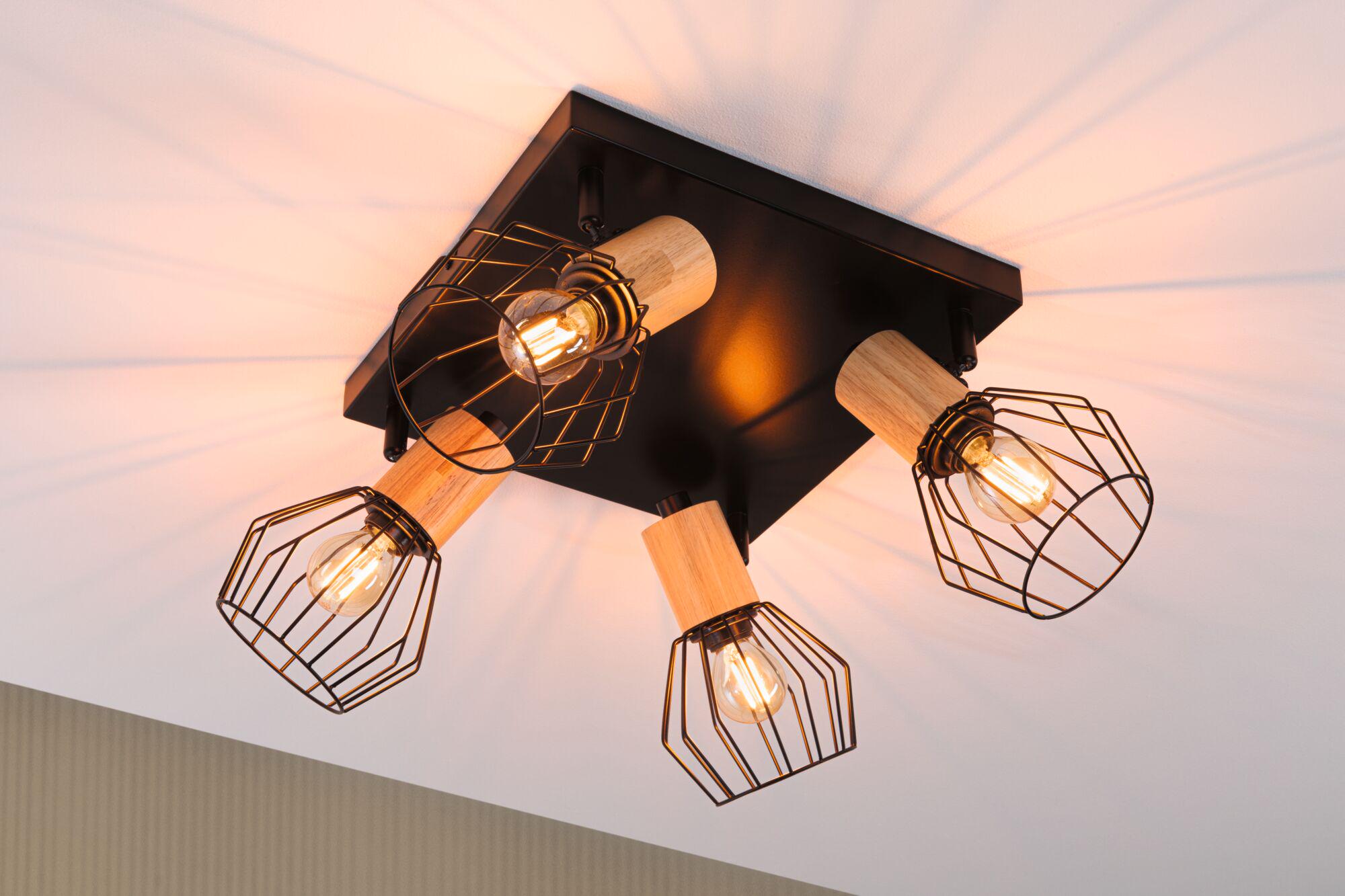 Deckenleuchte mit vier schwarzen Metallgitterschirmen und Holzdetails, warmes Licht für Wohnzimmer.