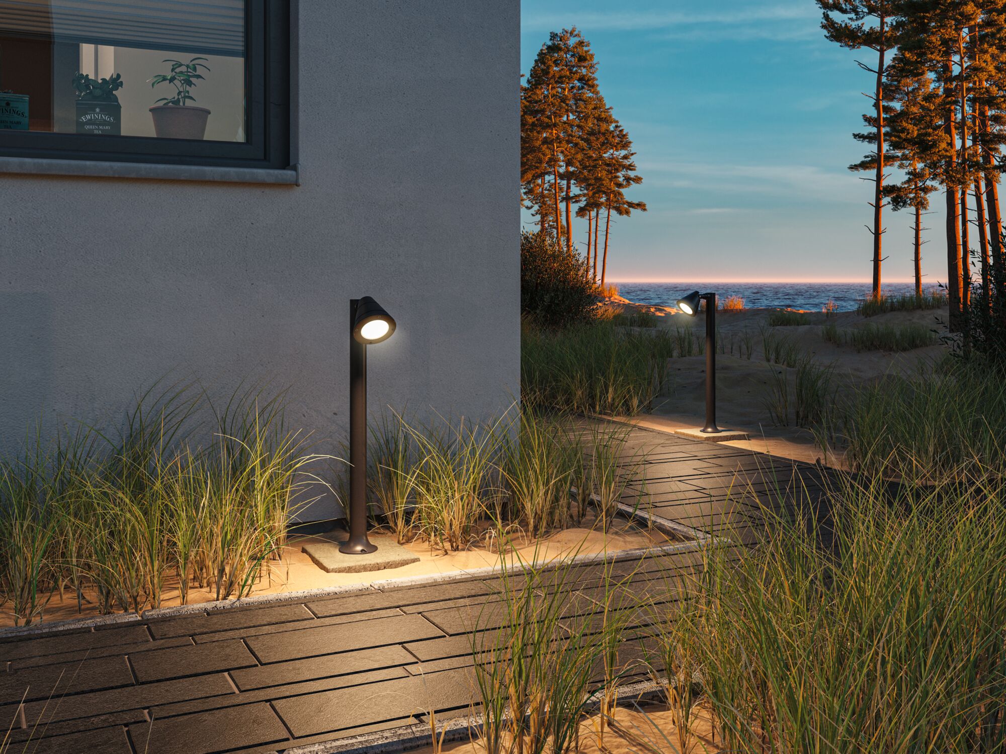 Zwarte metalen buitenmuurlamp verlicht zanderig pad met gras bij huis bij zonsondergang