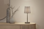 Modern table lamp with grey fabric shade and metal base on light wood sideboard with decor.