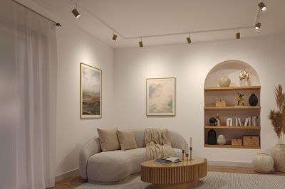 Living room with cream sofa, wooden coffee table and modern ceiling spotlights in warm white lighting