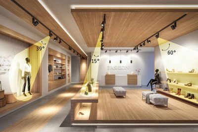 Modernes Modegeschäft mit Holzdecke und schwarzen LED-Strahlern, die Kleidung und Schuhe beleuchten