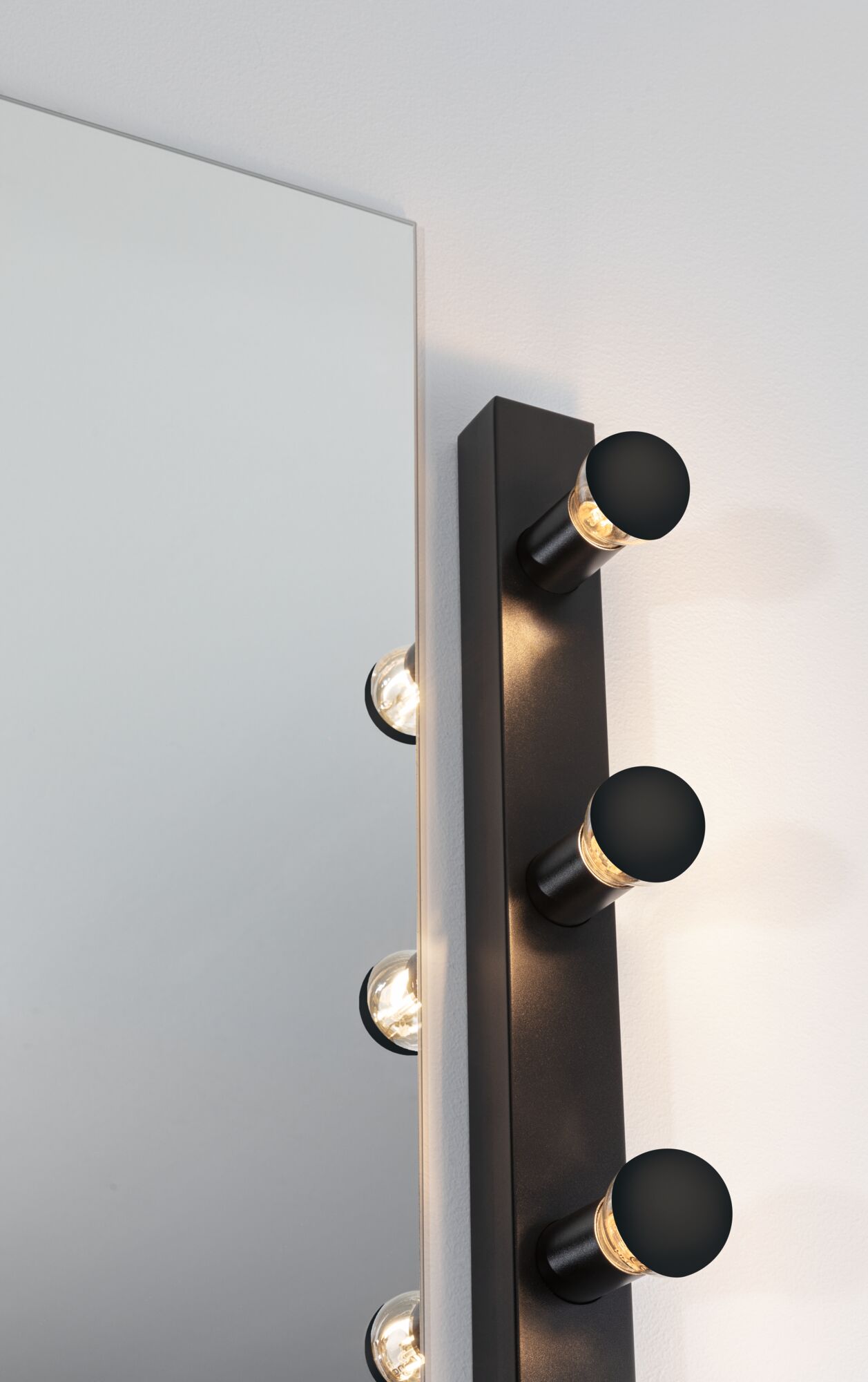 Black wall lamp with three round LED lights beside large mirror for modern home lighting