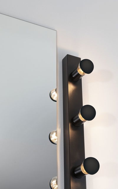 Black wall lamp with three round LED lights beside large mirror for modern home lighting