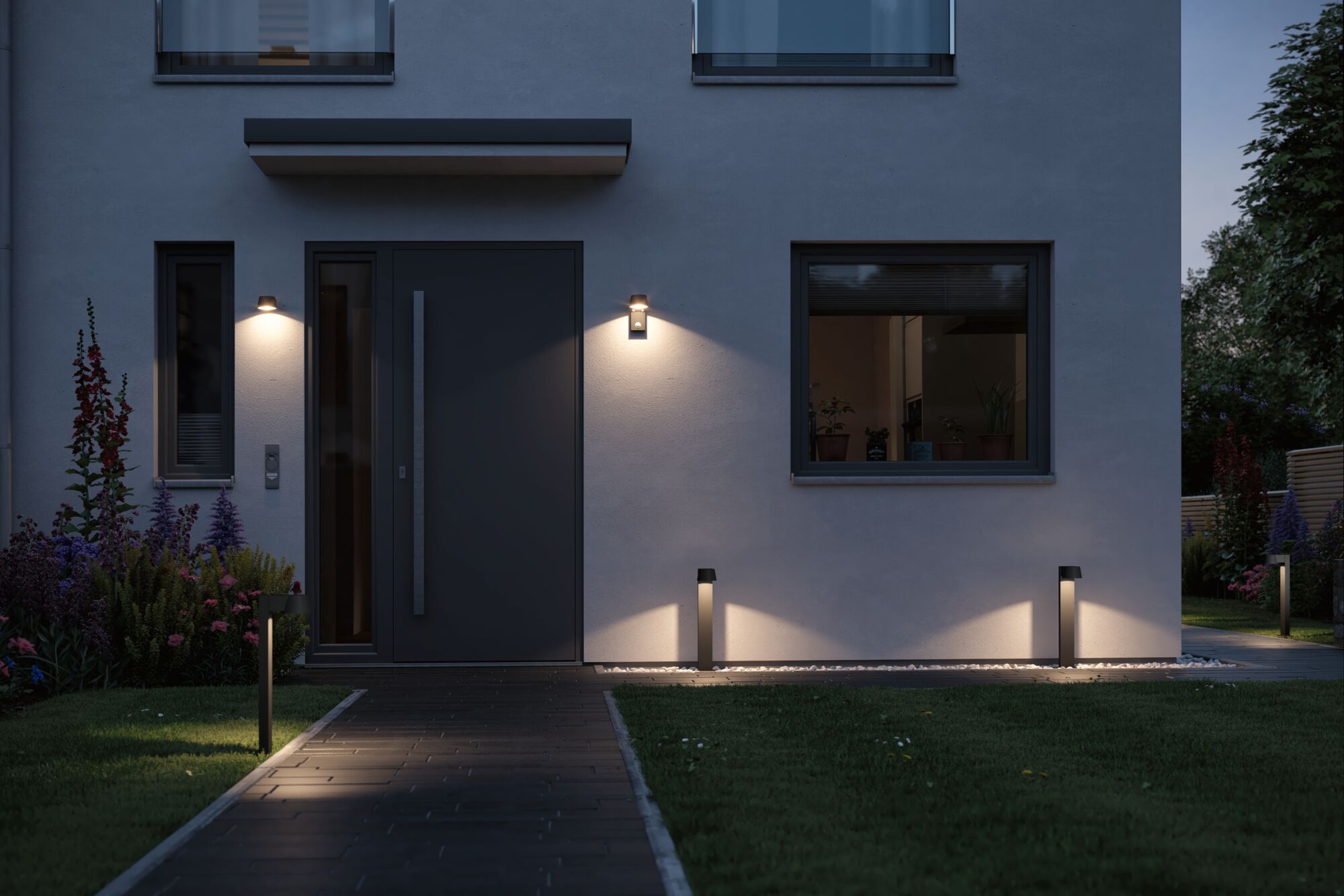 Moderne buitenverlichting met zwarte LED-wandlampen en paaltjes langs huisgevel en tuinpad