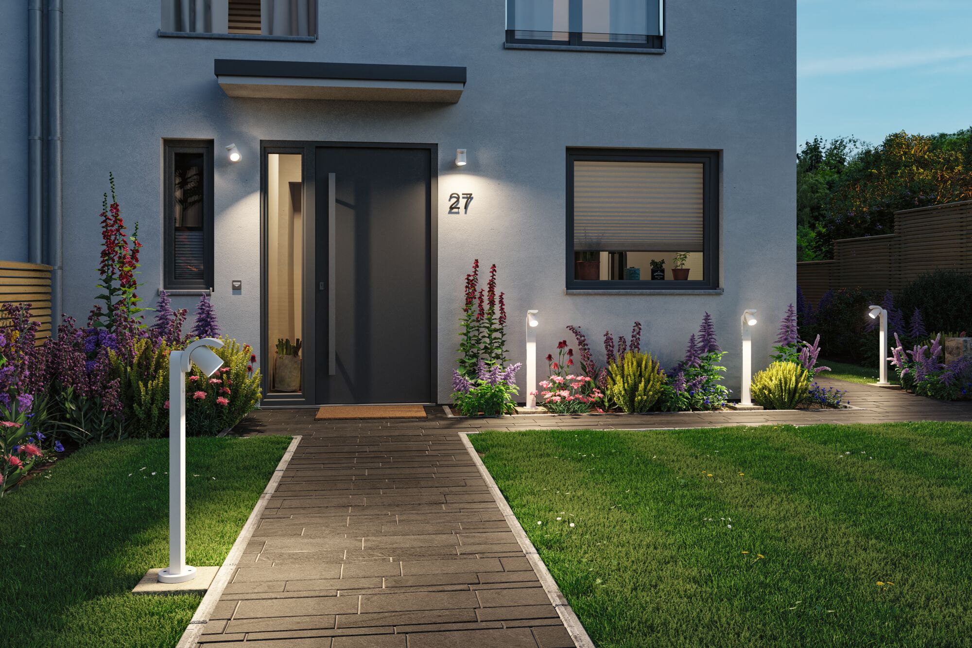 Moderner weißer Außenstrahler aus Metall beleuchtet Gartenweg und Hauseingang mit Pflanzen und Rasen.