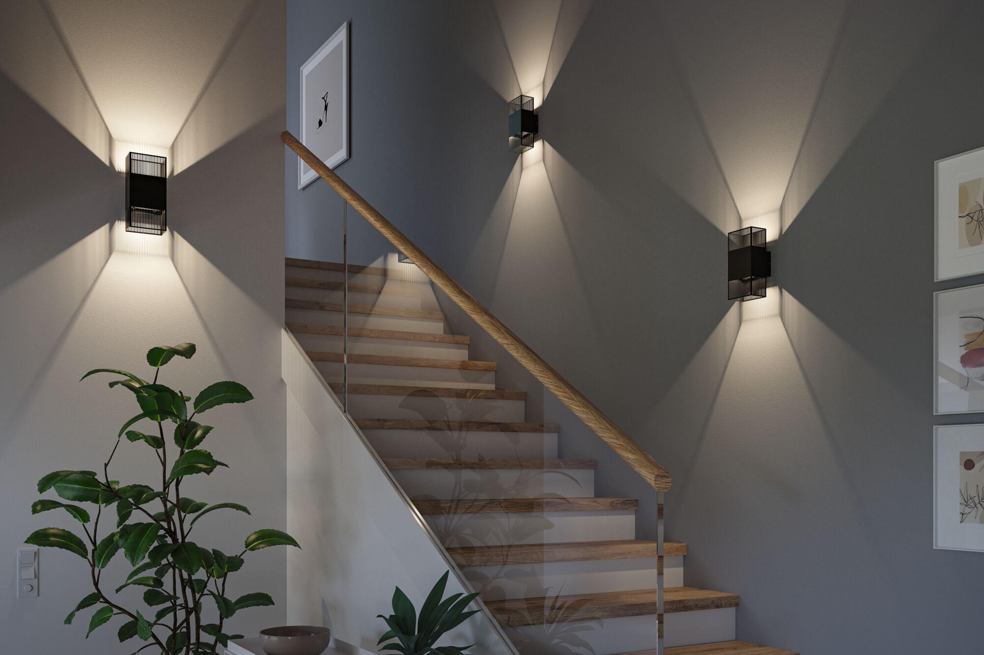 Modern black metal wall light with decorative light pattern on stairwell wall for home lighting