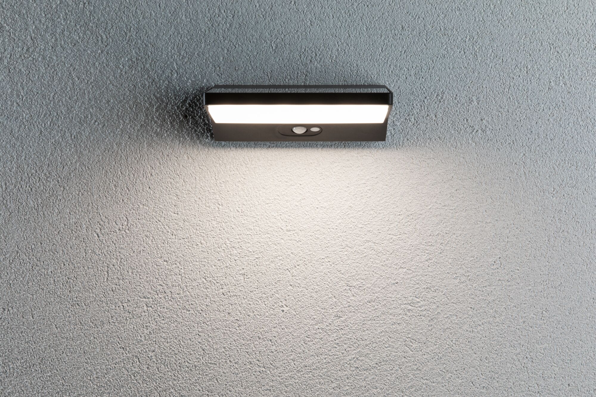 Zwarte LED-wandlamp met bewegingssensor op grijze muur, energiezuinige buitenverlichting
