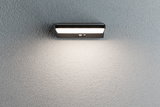 Black LED wall light with motion sensor on grey wall, energy-efficient outdoor lighting