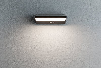 Applique murale LED noire avec détecteur de mouvement sur mur gris, éclairage extérieur économique
