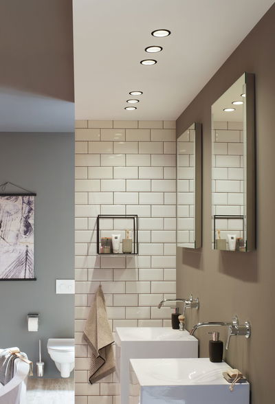 Modernes Badezimmer mit weißen Keramikwaschbecken, Wandarmaturen und LED-Einbaustrahlern in neutralen Farben
