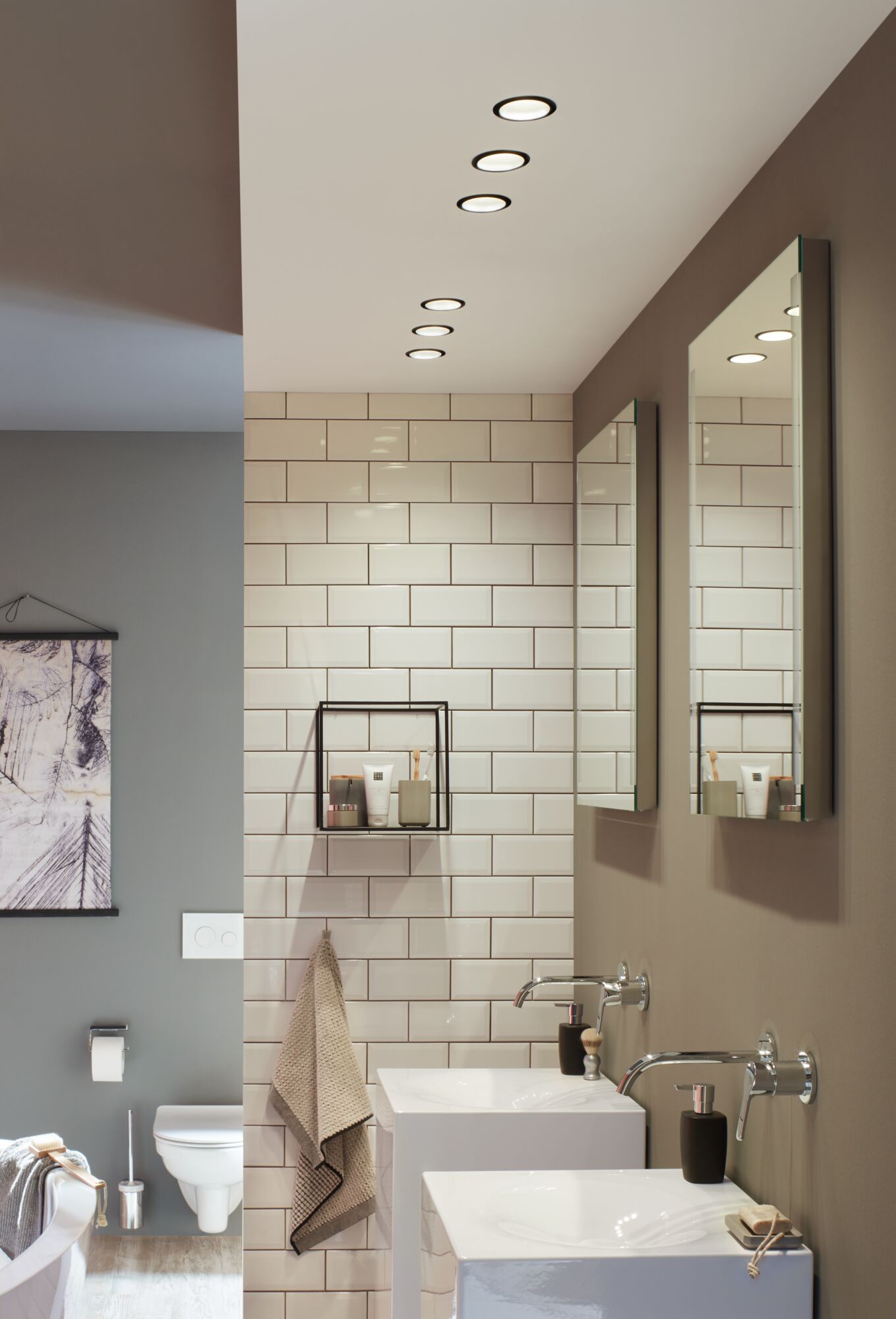 Salle de bain moderne avec lavabos en céramique blanche, robinets muraux et spots LED encastrés aux tons neutres