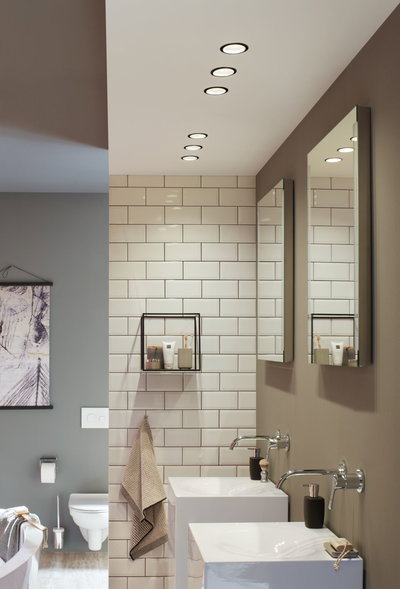 Salle de bain moderne avec lavabos en céramique blanche, robinets muraux et spots LED encastrés aux tons neutres