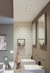 Modernes Badezimmer mit weißen Keramikwaschbecken, Wandarmaturen und LED-Einbaustrahlern in neutralen Farben