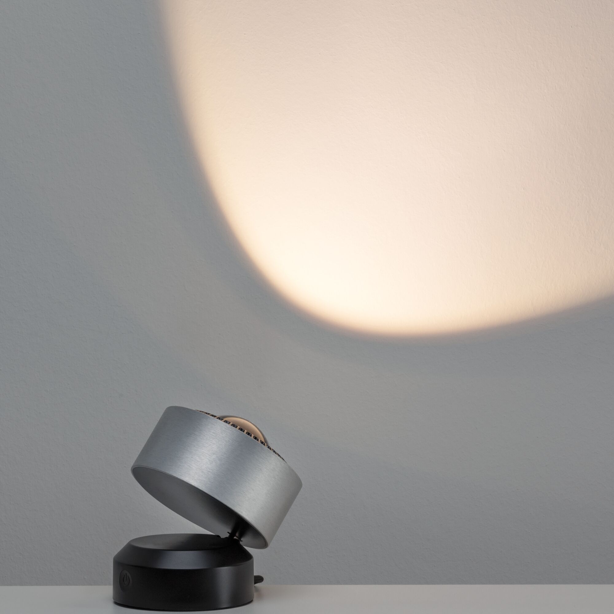 Moderner LED-Tischstrahler aus gebürstetem Aluminium in Silber und Schwarz mit warmweißem Licht.