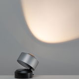 Moderner LED-Tischstrahler aus gebürstetem Aluminium in Silber und Schwarz mit warmweißem Licht.