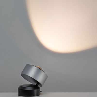 Moderner LED-Tischstrahler aus gebürstetem Aluminium in Silber und Schwarz mit warmweißem Licht.