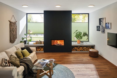Gezellige woonkamer met witte bank, houten vloer, zwarte open haard en moderne plafondlampen.