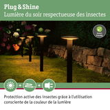 Quatre lampes de jardin LED noires avec lumière blanche chaude respectueuse des insectes dans un jardin.